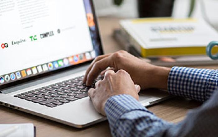 Uno studente appoggia le due mani su un laptop per digitare